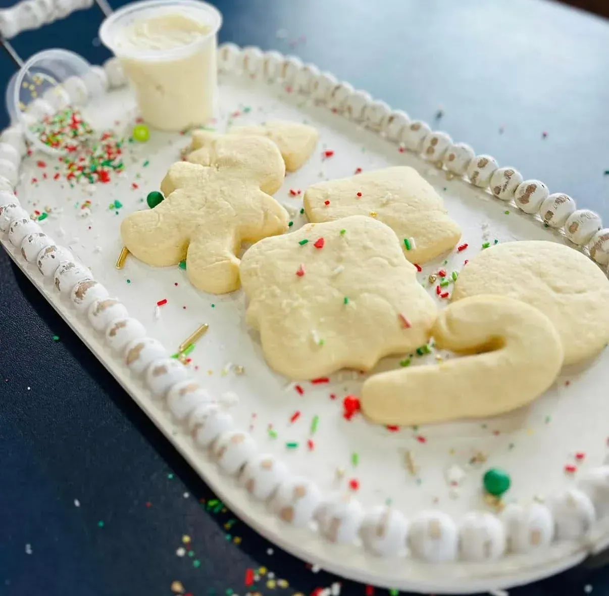 Cookies on a white tray with frosting and sprinkles.