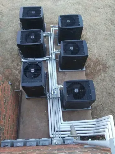 Six rooftop HVAC units with silver piping and electrical boxes.