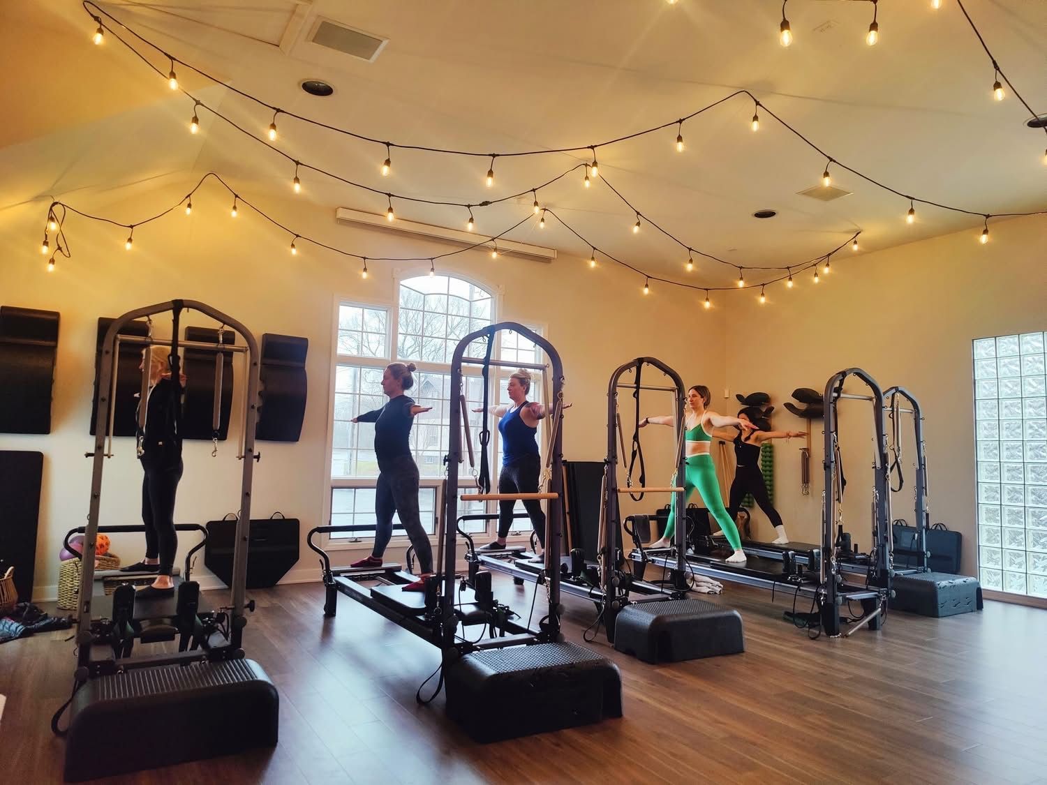 Clients are doing pilates on reformers in a large room.