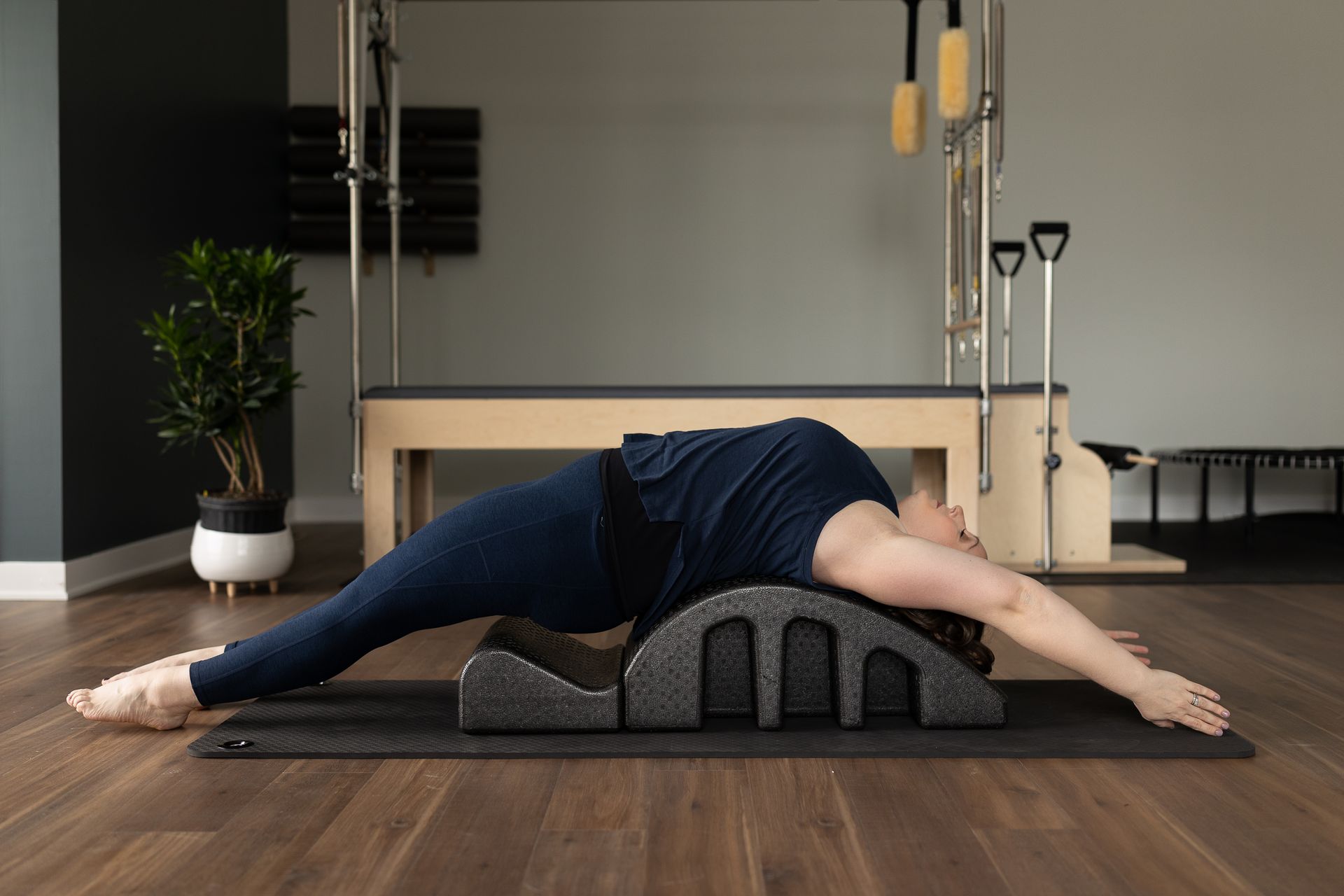 A woman is stretching on a yoga mat assisted by specialty foam blocks and equipment