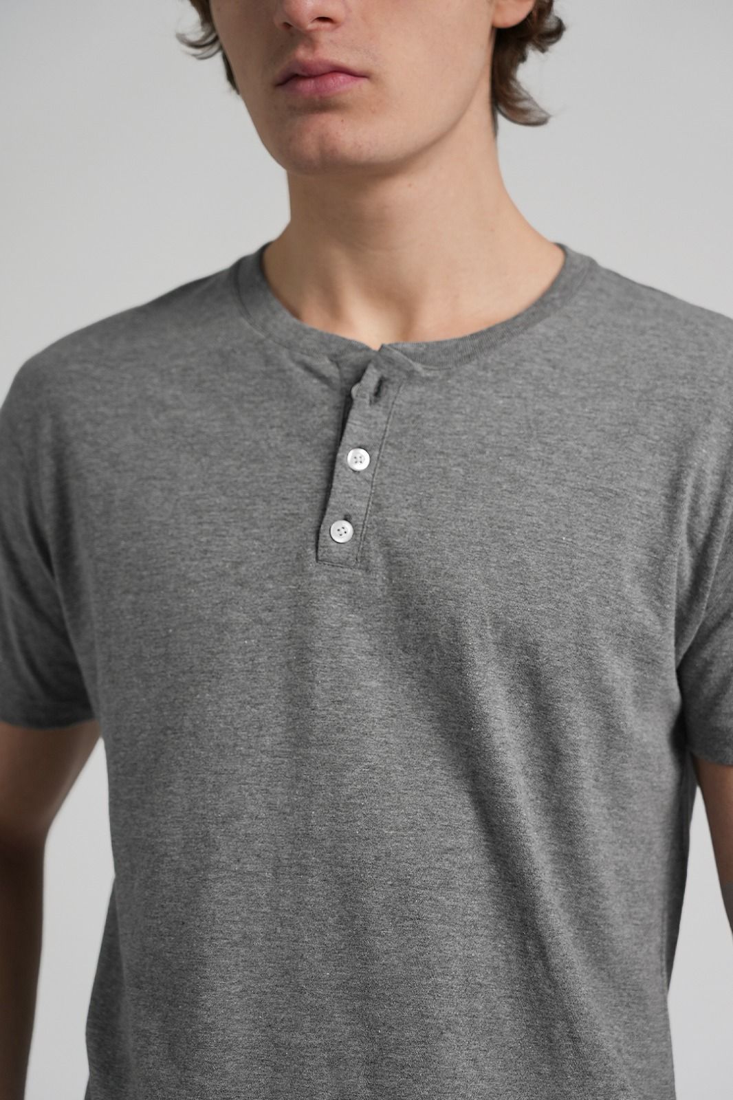 Camisa Henley gris con mangas cortas y tapeta de tres botones.