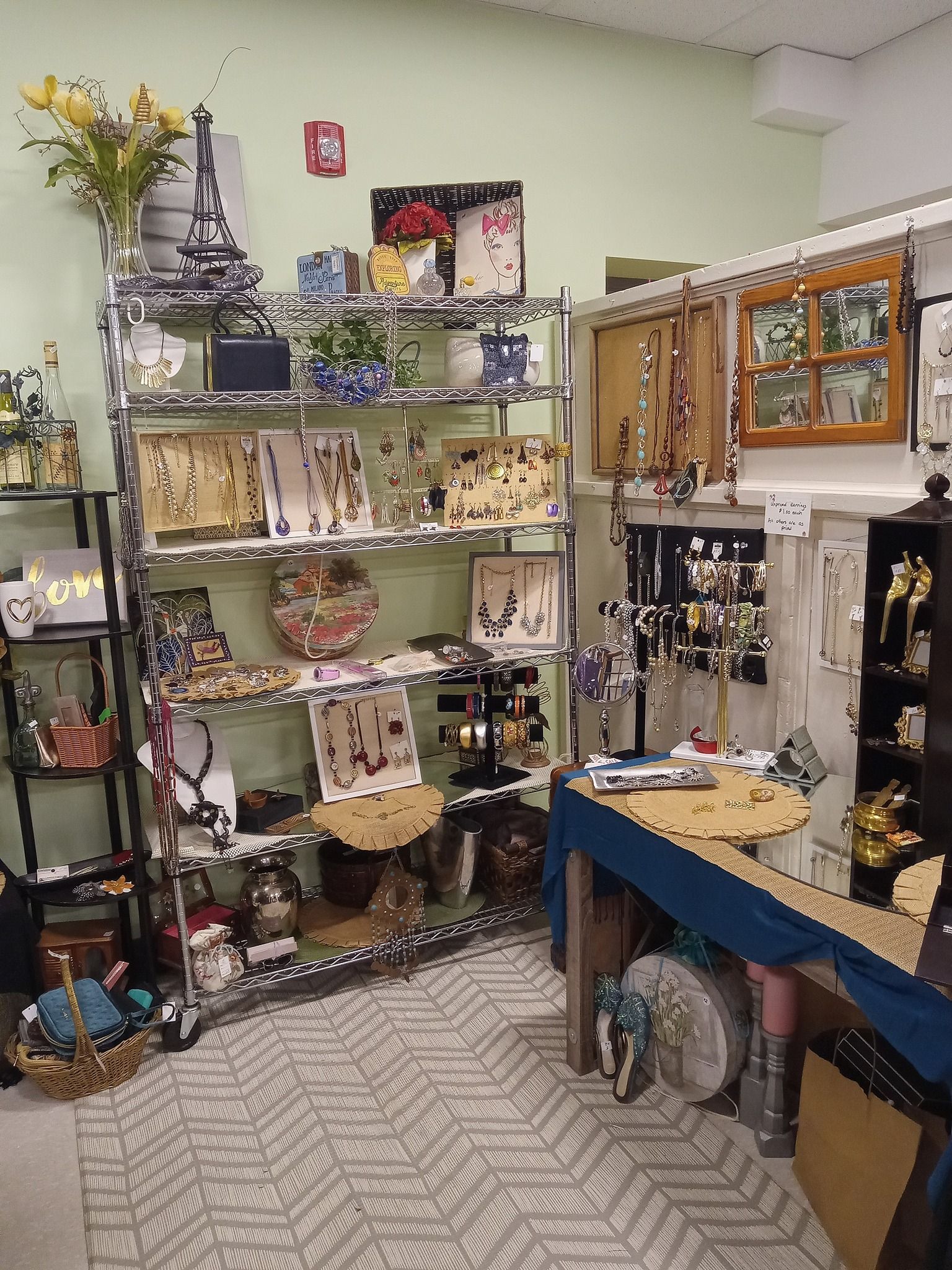 Two walls neatly set up with framed corkboards, jewelry hanging and pinned into the corkboards.