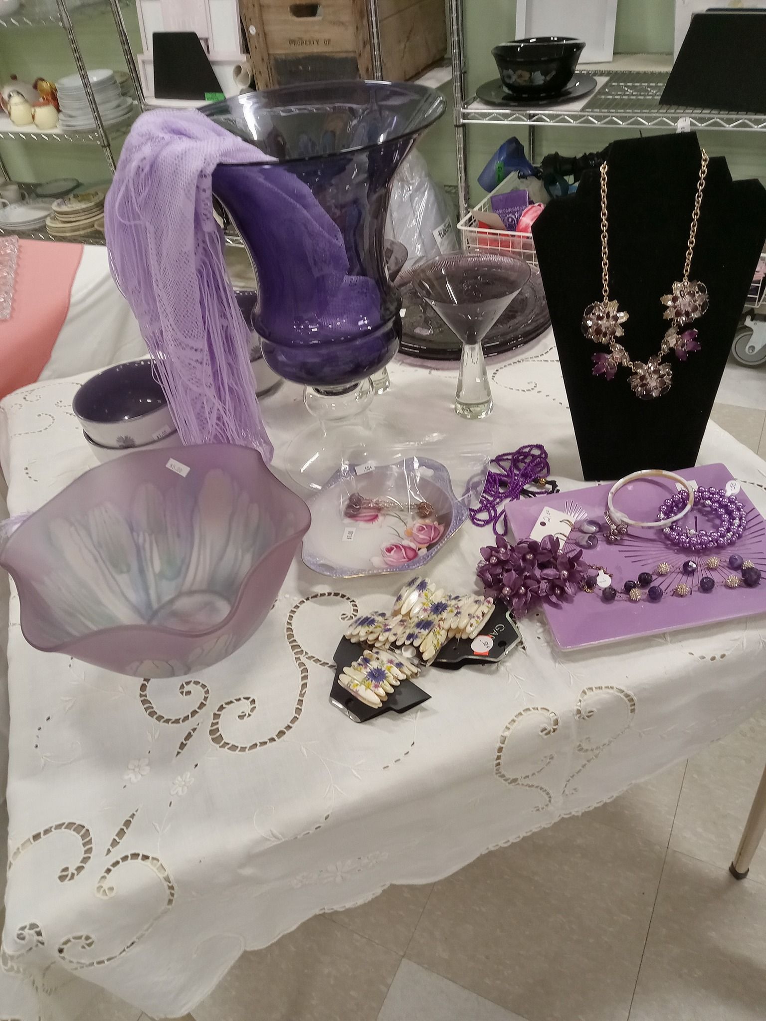 Tabletop of various purple items: vases, scarves, jewelry, and plates.