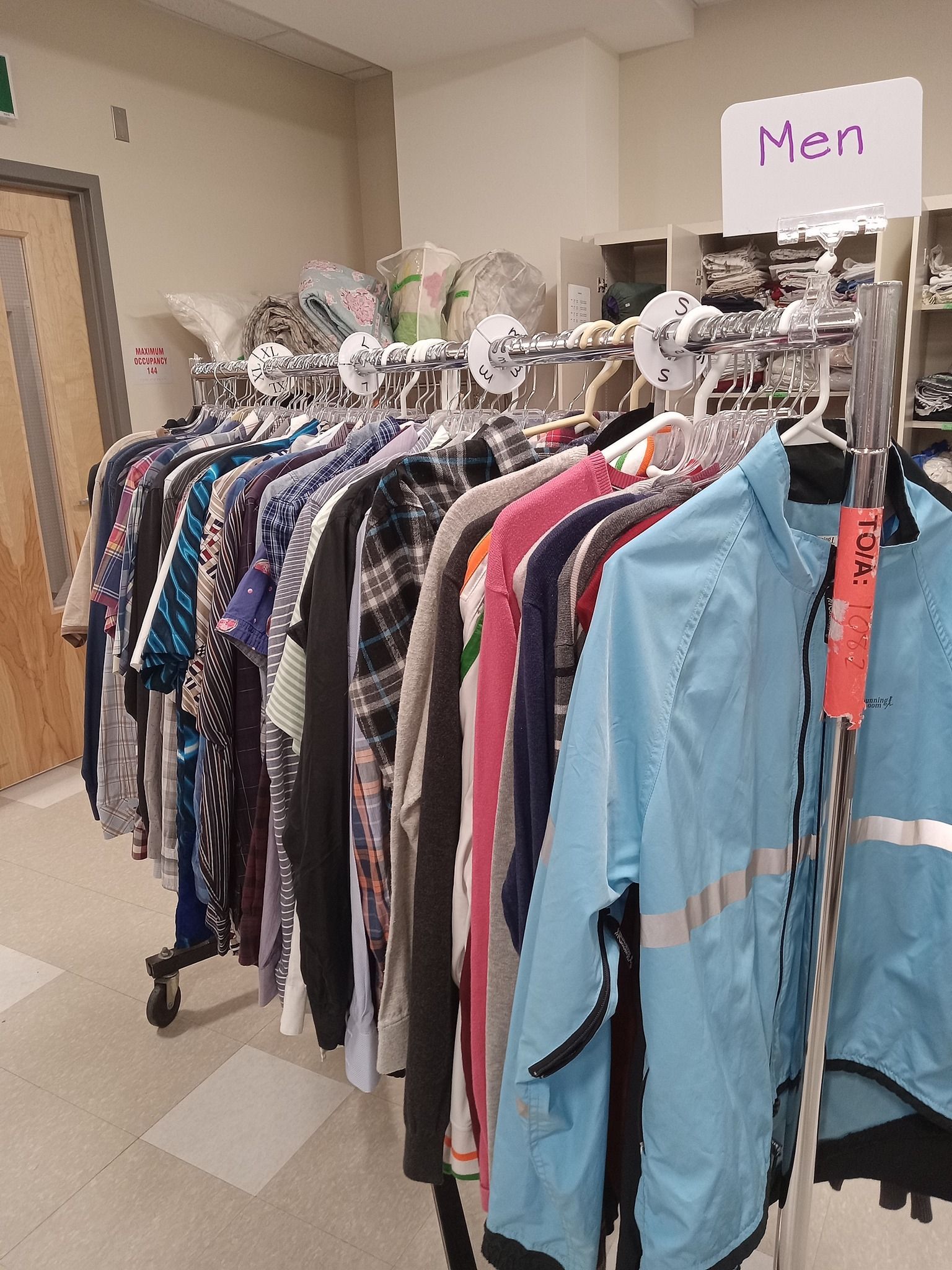 Metal clothing rack with men's shirts and jackets hanging on it.