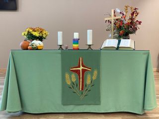 Our altar table with green tablecloth, candles, and autumnal decorations.