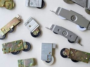 A collection of various metal and plastic sliding door or window roller hardware mechanisms on a white background.