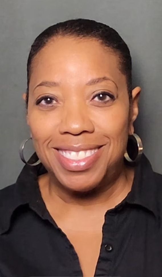 Woman with a bright smile wearing a black shirt and large hoop earrings.