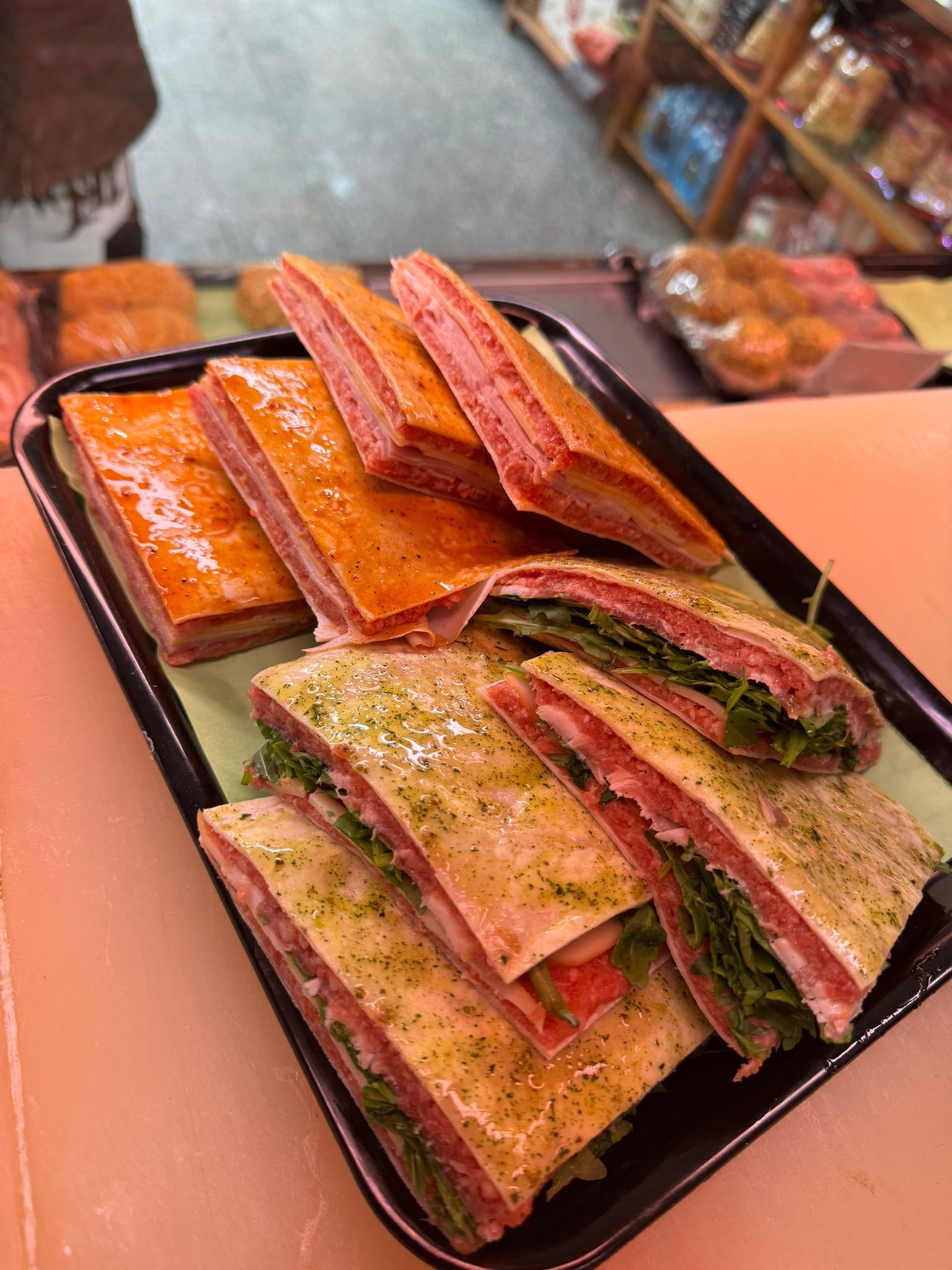 Panini disposti su un vassoio nero. Alcuni sono con carne, formaggio e lattuga. Altri sono semplici, con pane dorato.