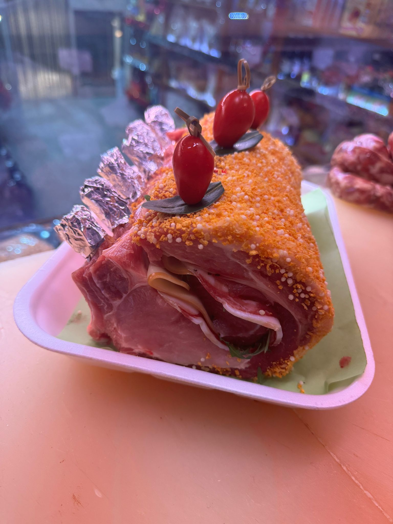 Arrosto di maiale impanato, avvolto in pancetta e verdure, guarnito con pomodori.