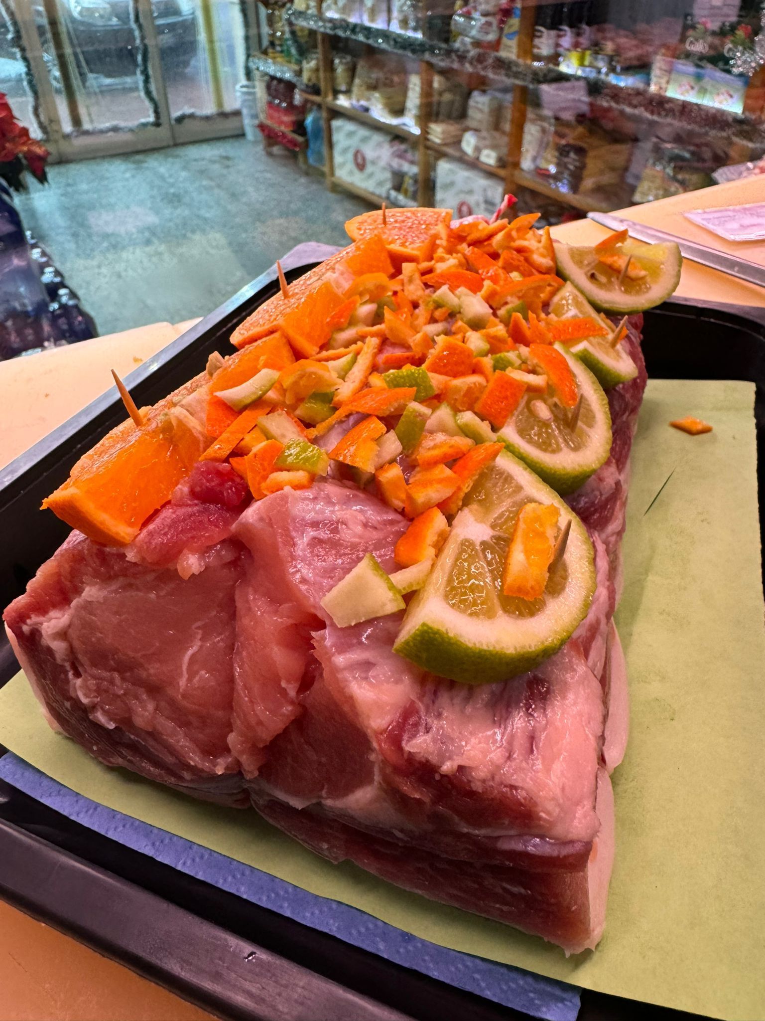 Arrosto di maiale crudo condito con fette e scorza di arancia e agrumi verdi.