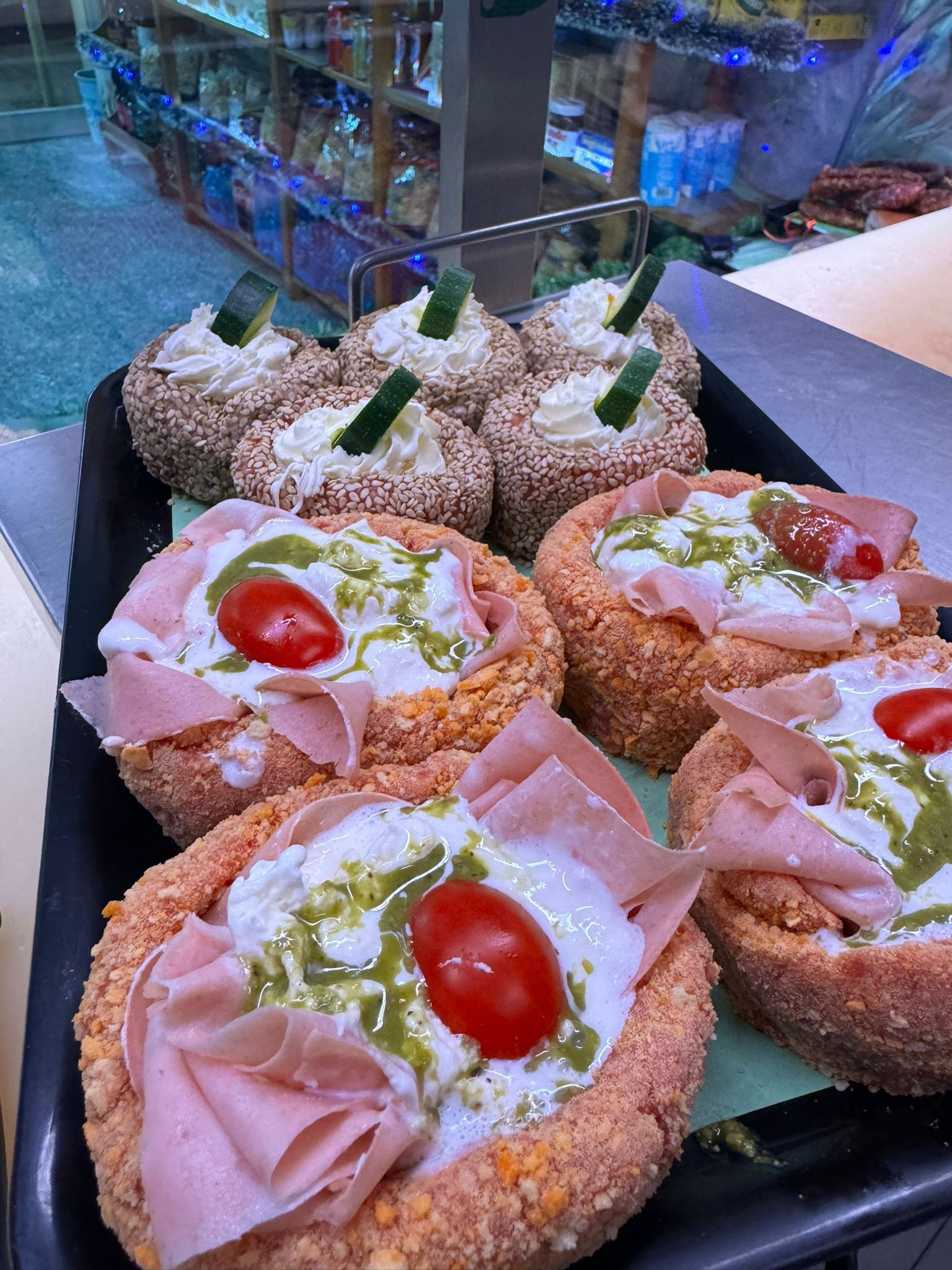 Vassoio di ciotole di pane salato riempite con condimenti. Alcune hanno prosciutto, formaggio, pesto e pomodori. Altre hanno un condimento diverso con erbe aromatiche.