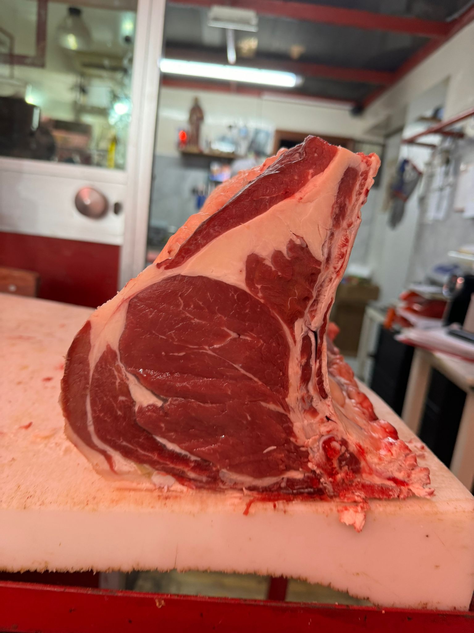 Grande bistecca di ribeye cruda con osso su ceppo bianco.