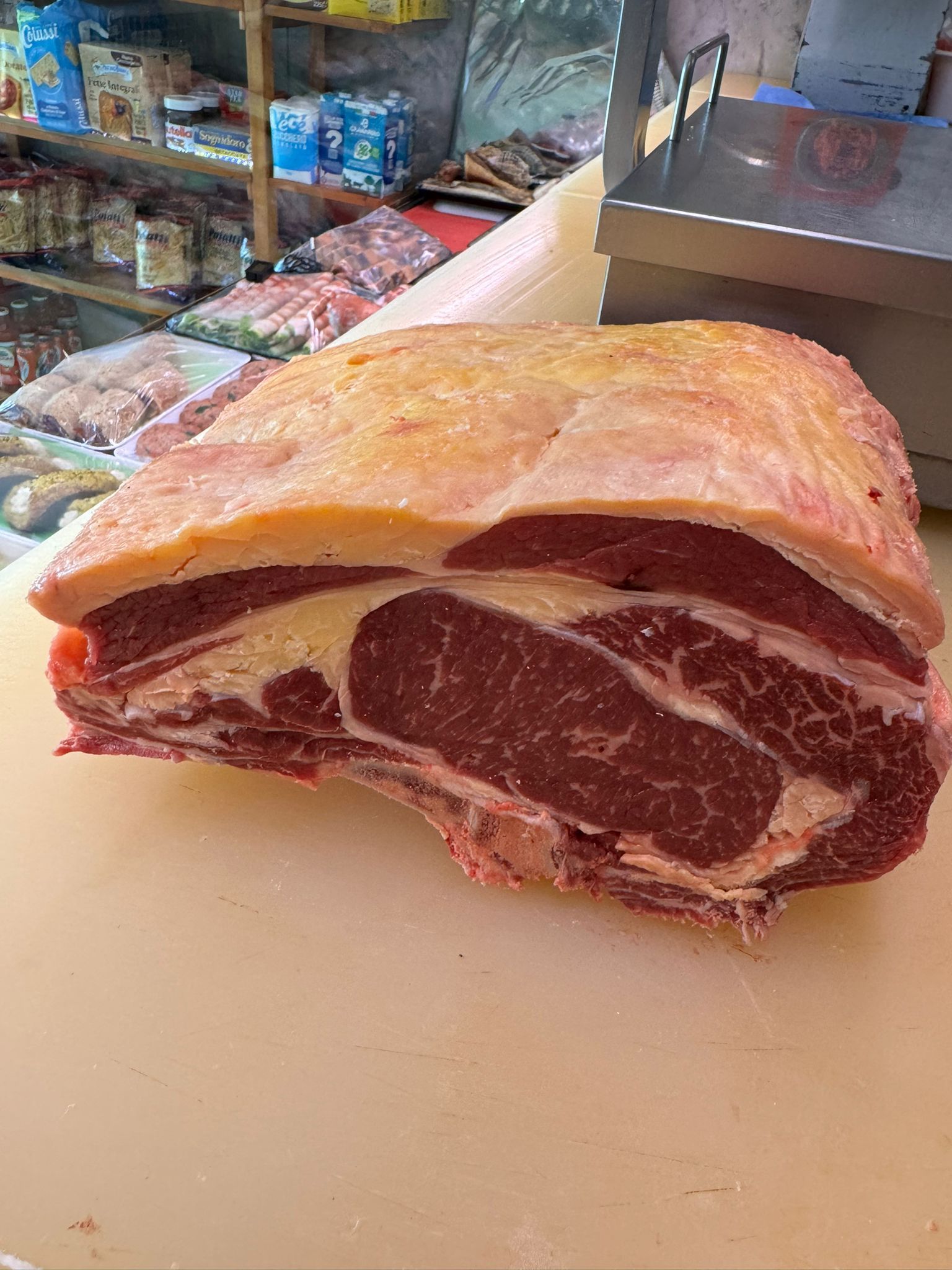 Grande arrosto di manzo crudo con grasso su un ceppo da macellaio.