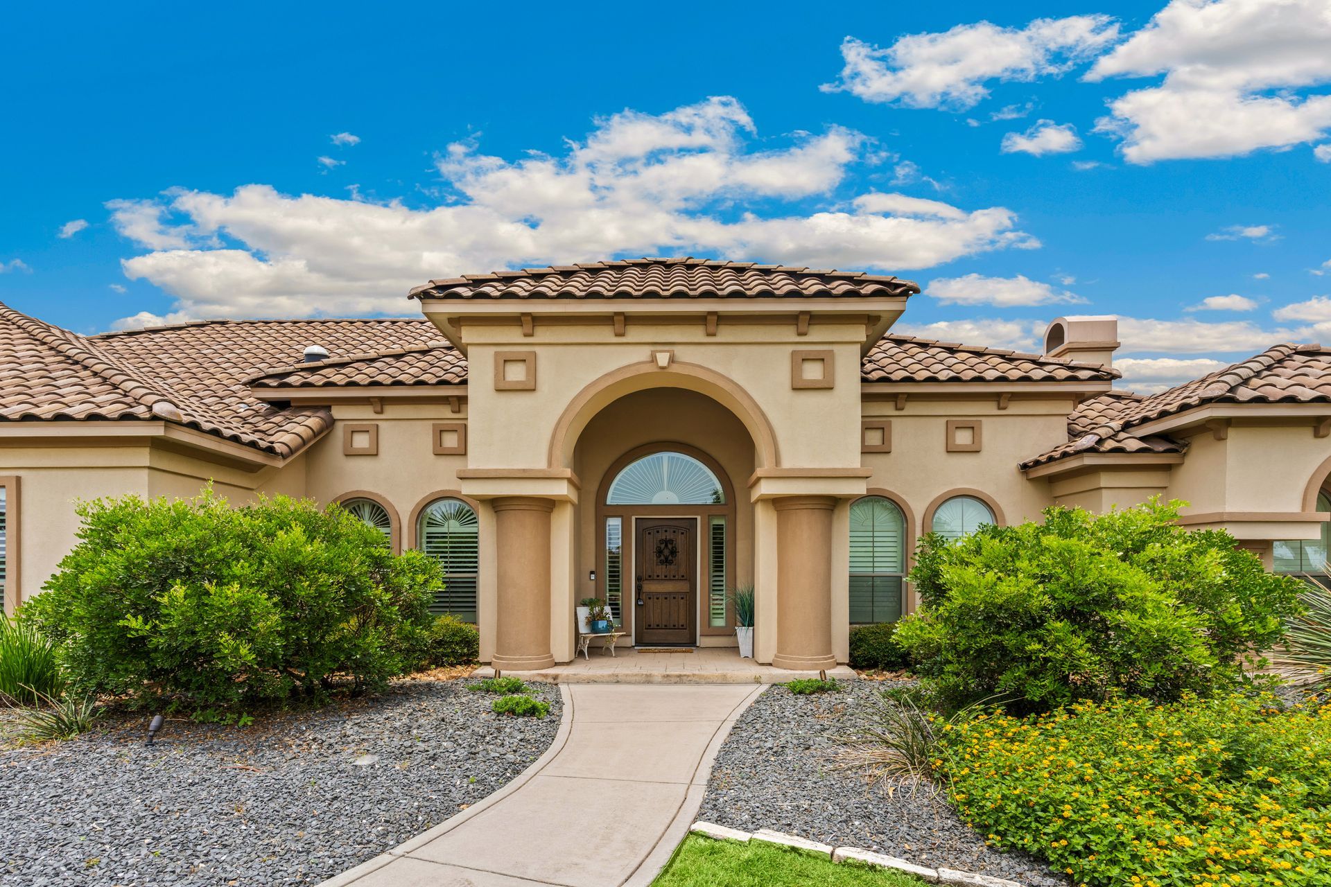 The front of a large house with a walkway leading to it.