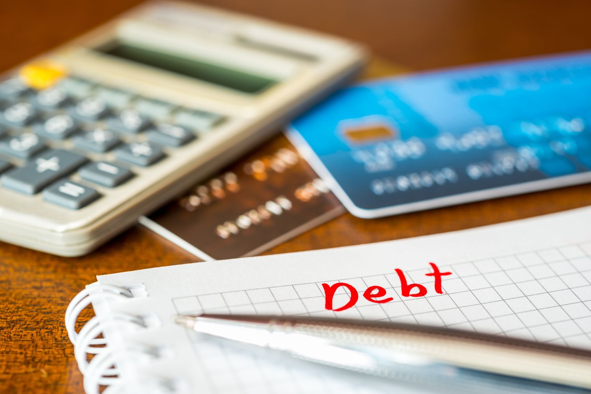 A calculator , credit cards , and a notebook with the word debt written on it.