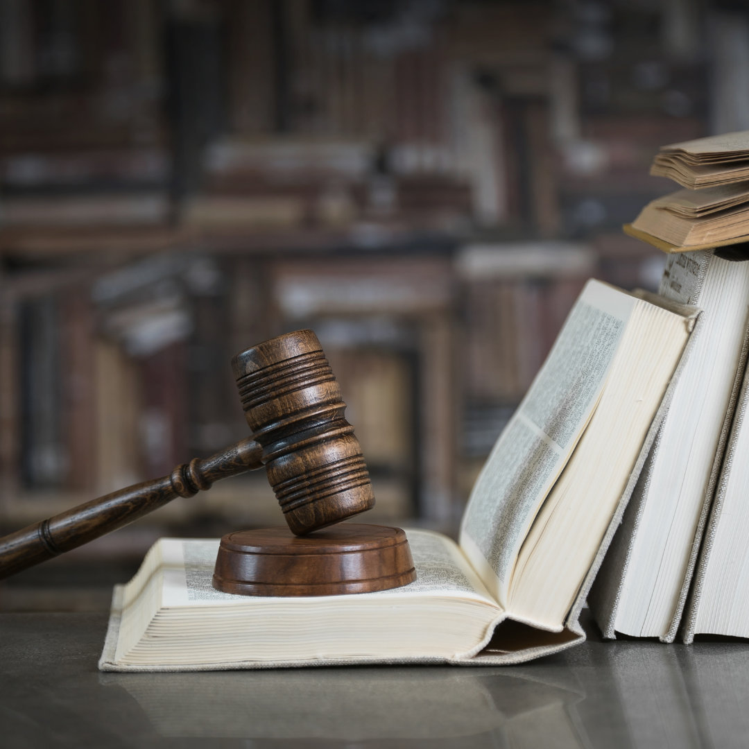 A wooden judge 's gavel is sitting on top of a stack of books.