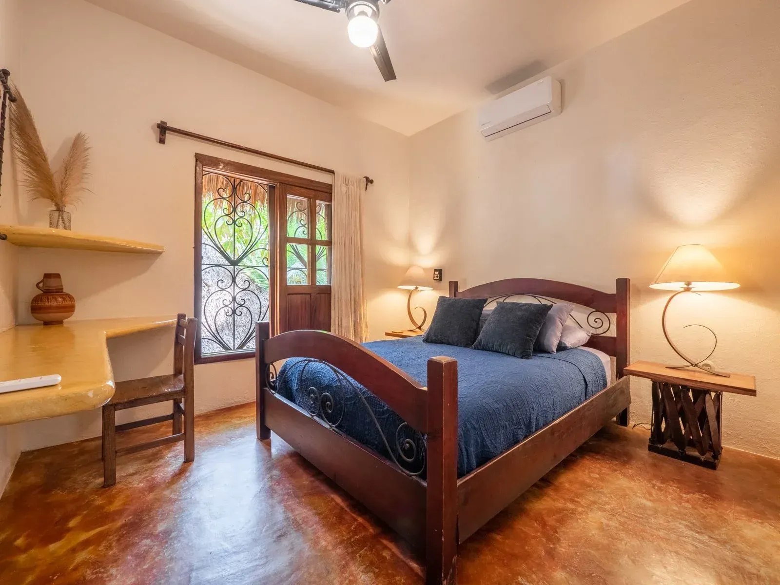 Bedroom with a wooden bed, desk, and a window overlooking greenery.