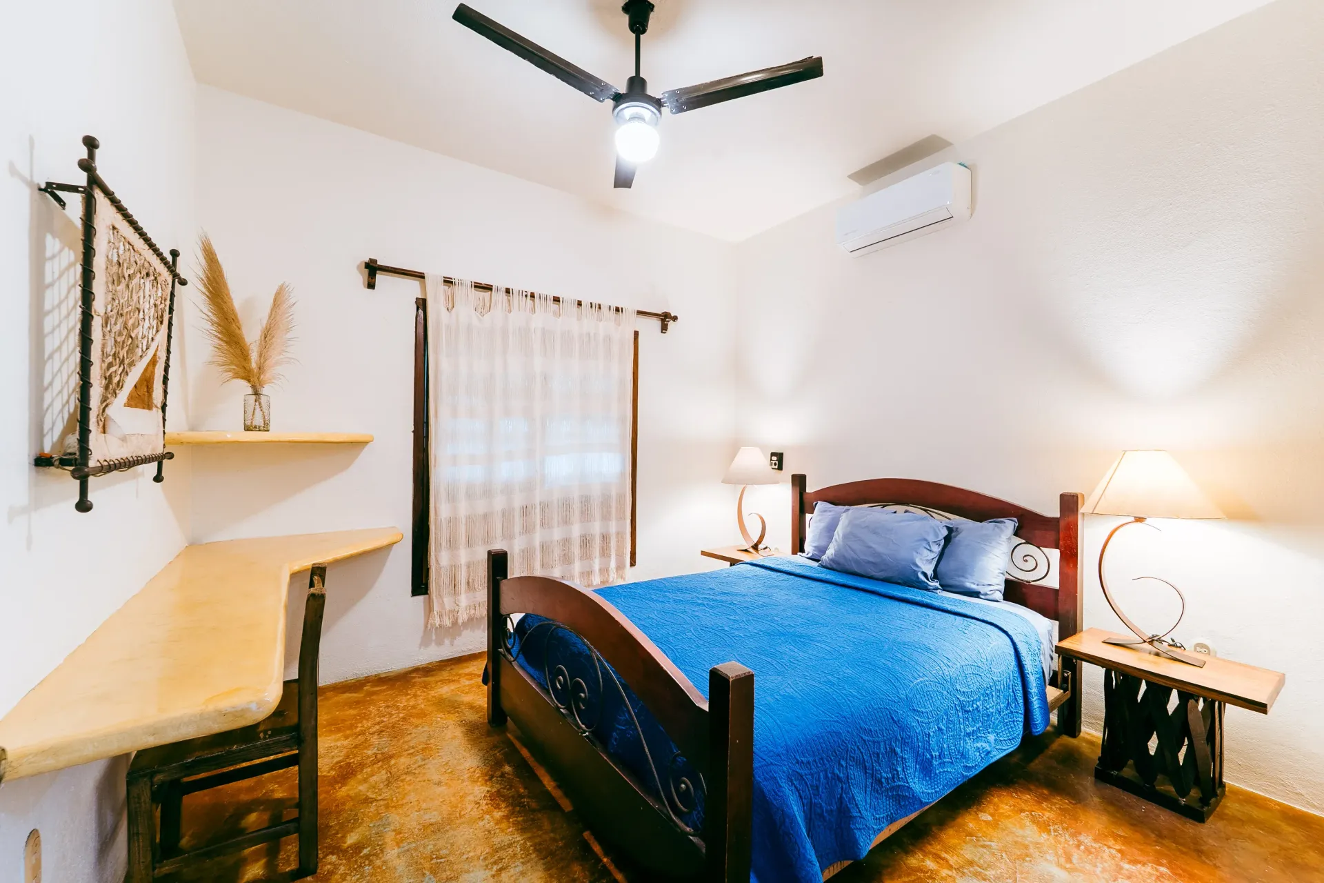 Bedroom with a wooden bed, blue bedding, wooden desk, and a ceiling fan.