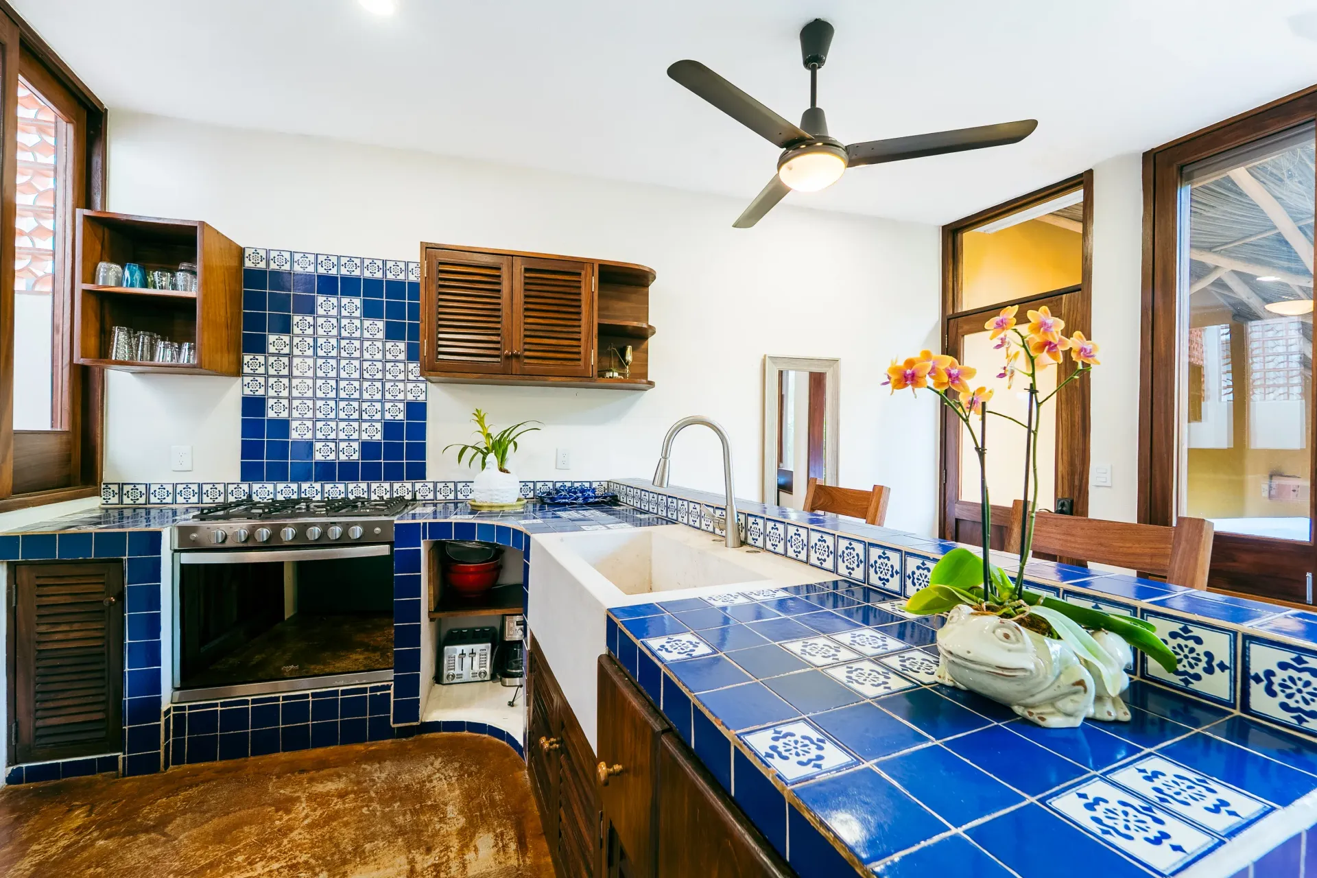 Kitchen with blue and white tile countertops and backsplash, wood cabinets, and an open oven.