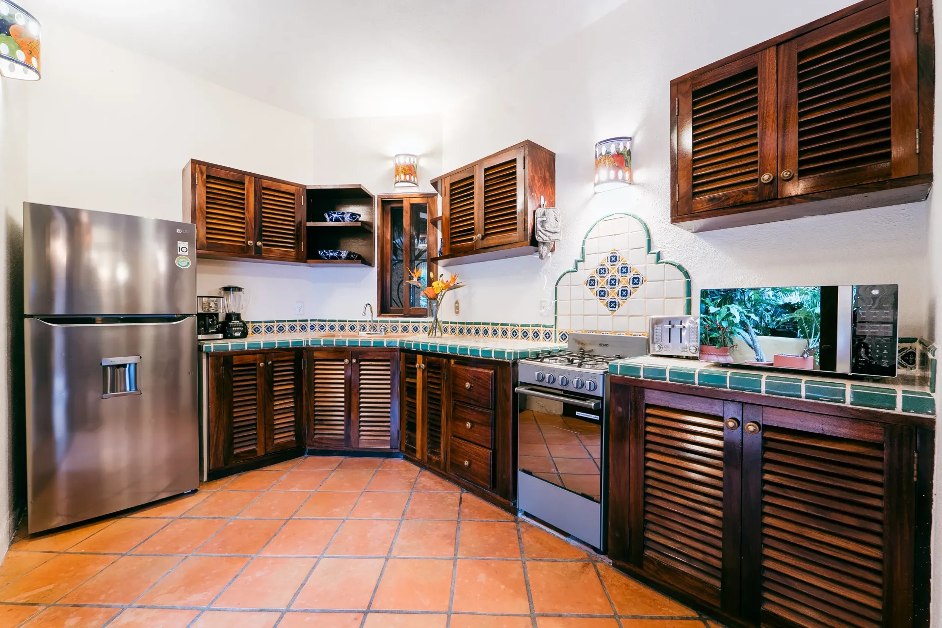 Kitchen with dark wood cabinets, stainless steel refrigerator, and terracotta tile flooring.