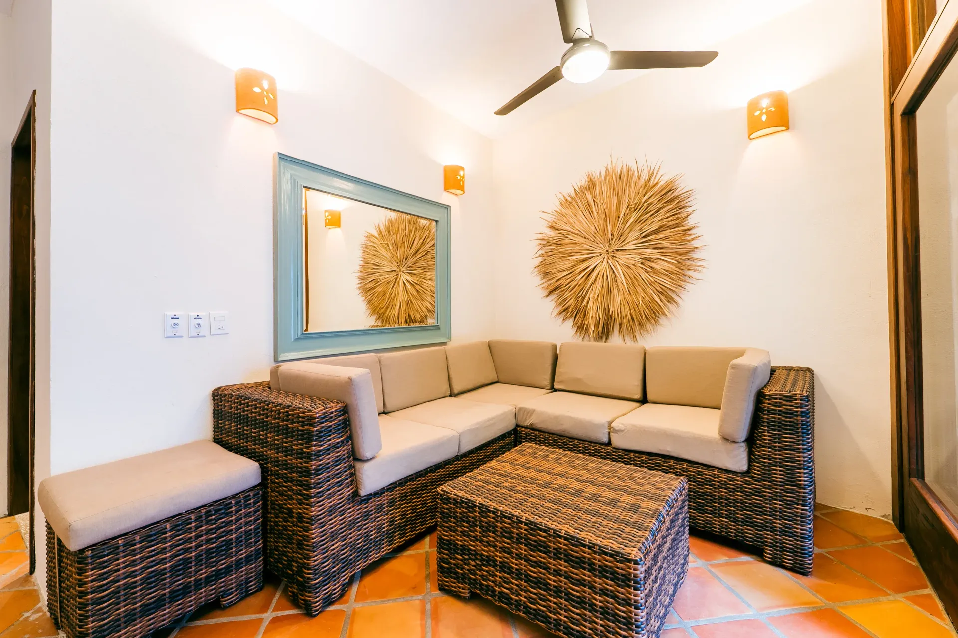 Cozy outdoor seating area with wicker furniture, neutral cushions, and decorative wall art.