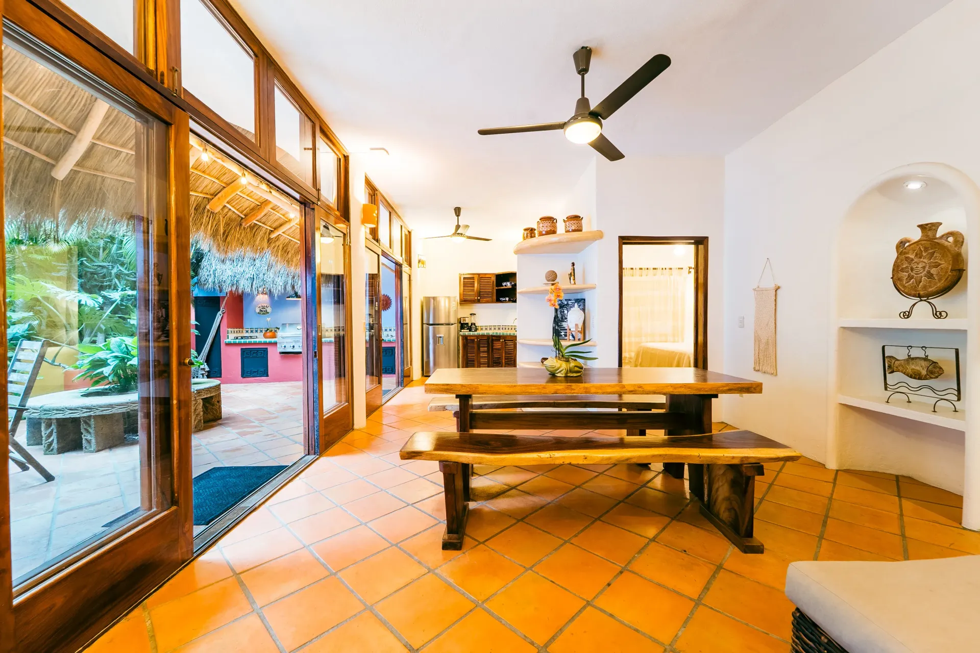 Open dining room with wooden table, benches, and outdoor access.