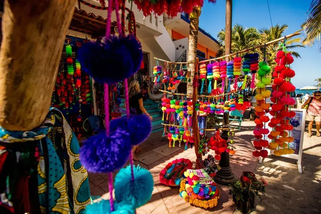 Colorful crafts and souvenirs at an outdoor market stall, including pom-poms, bags, and woven items.