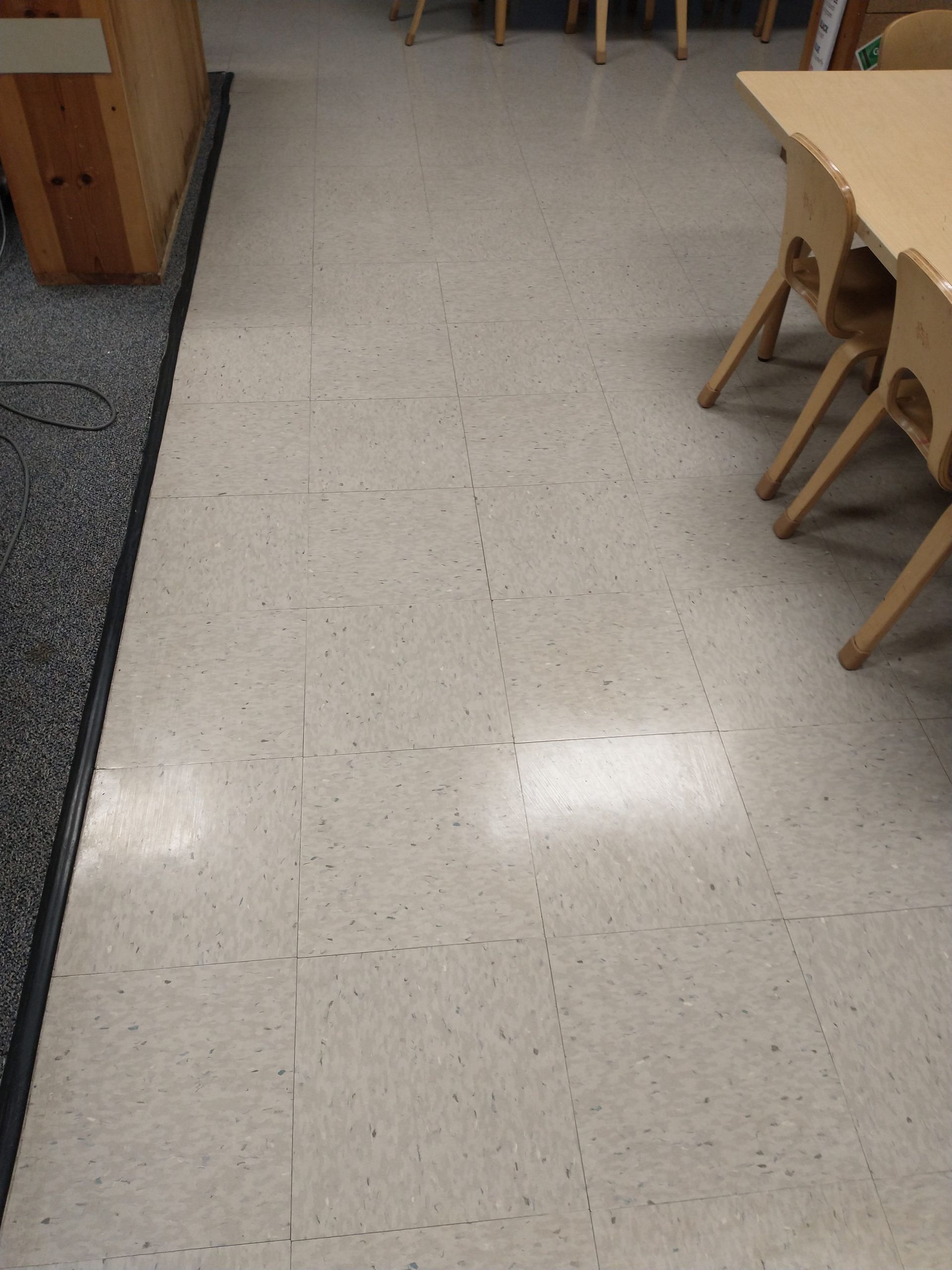 Empty classroom floor with tables and chairs along the right side.