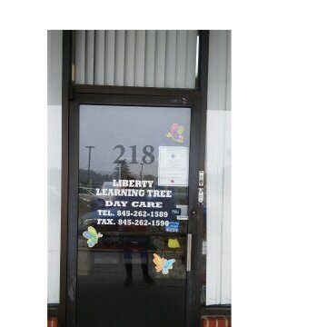Glass storefront door with “218,” “Berry Learning Tree Daycare,” phone numbers, and butterfly decals