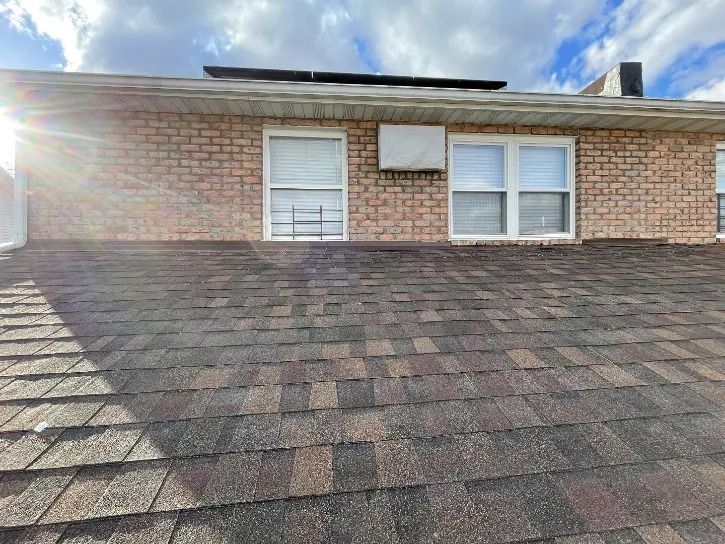 A brick house with a roof and a lot of windows.