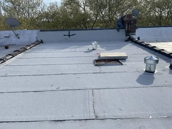 A roof with a chimney and satellite dishes on it