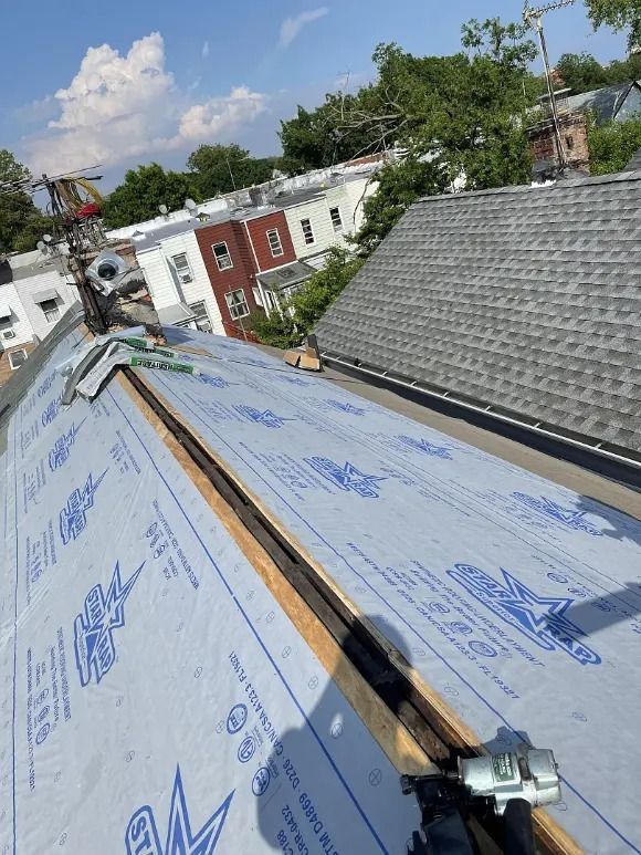 A roof is being covered with a blue tarp.