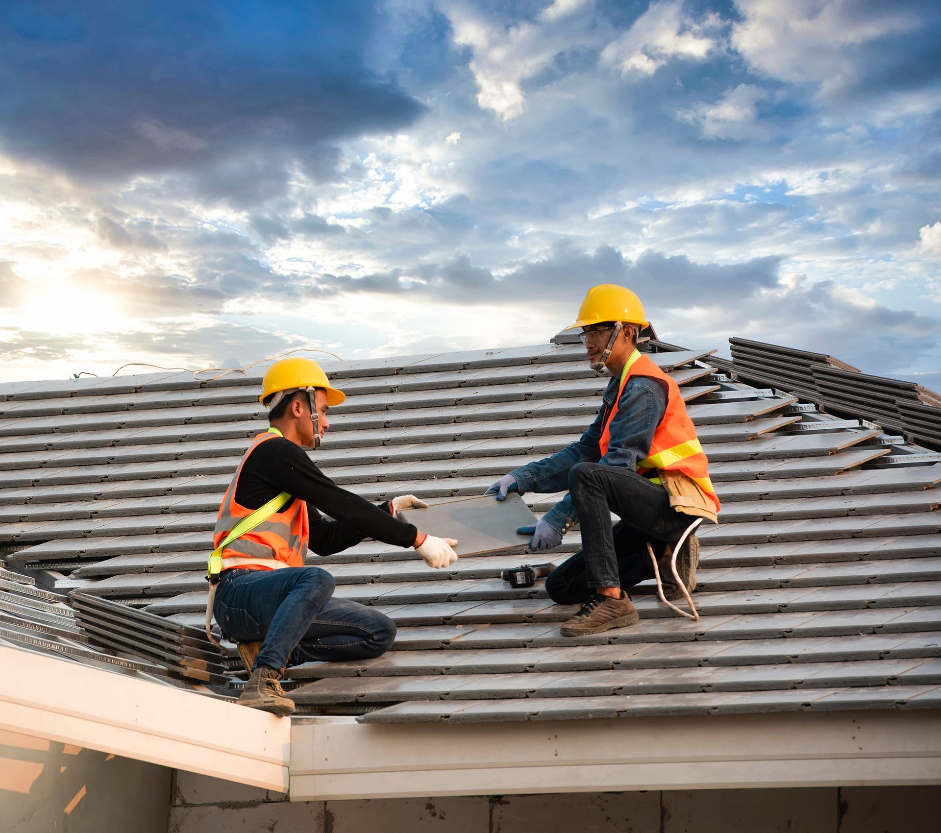 Two construction workers are working on the roof of a house.