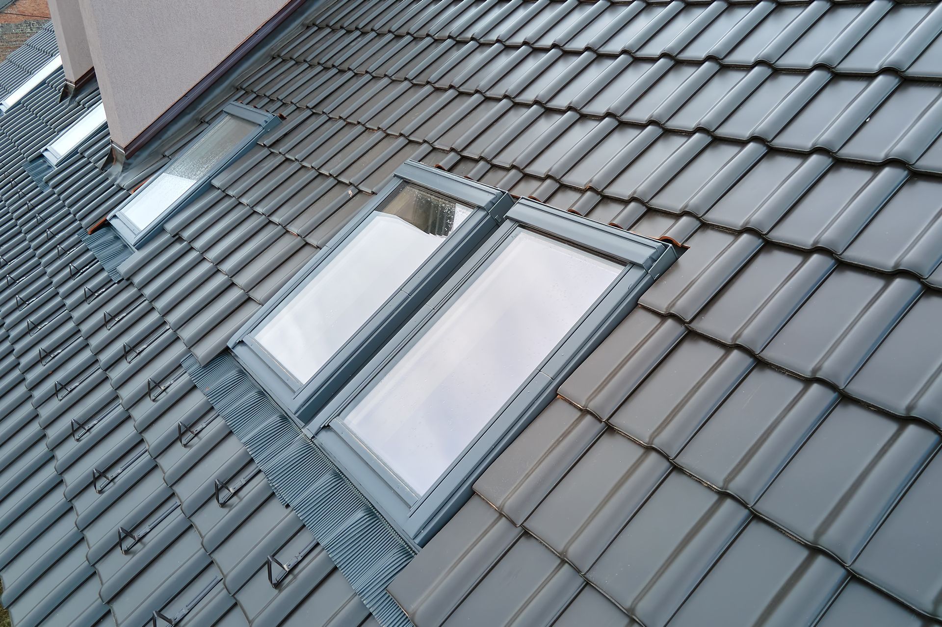 A roof with two skylights on it and a chimney