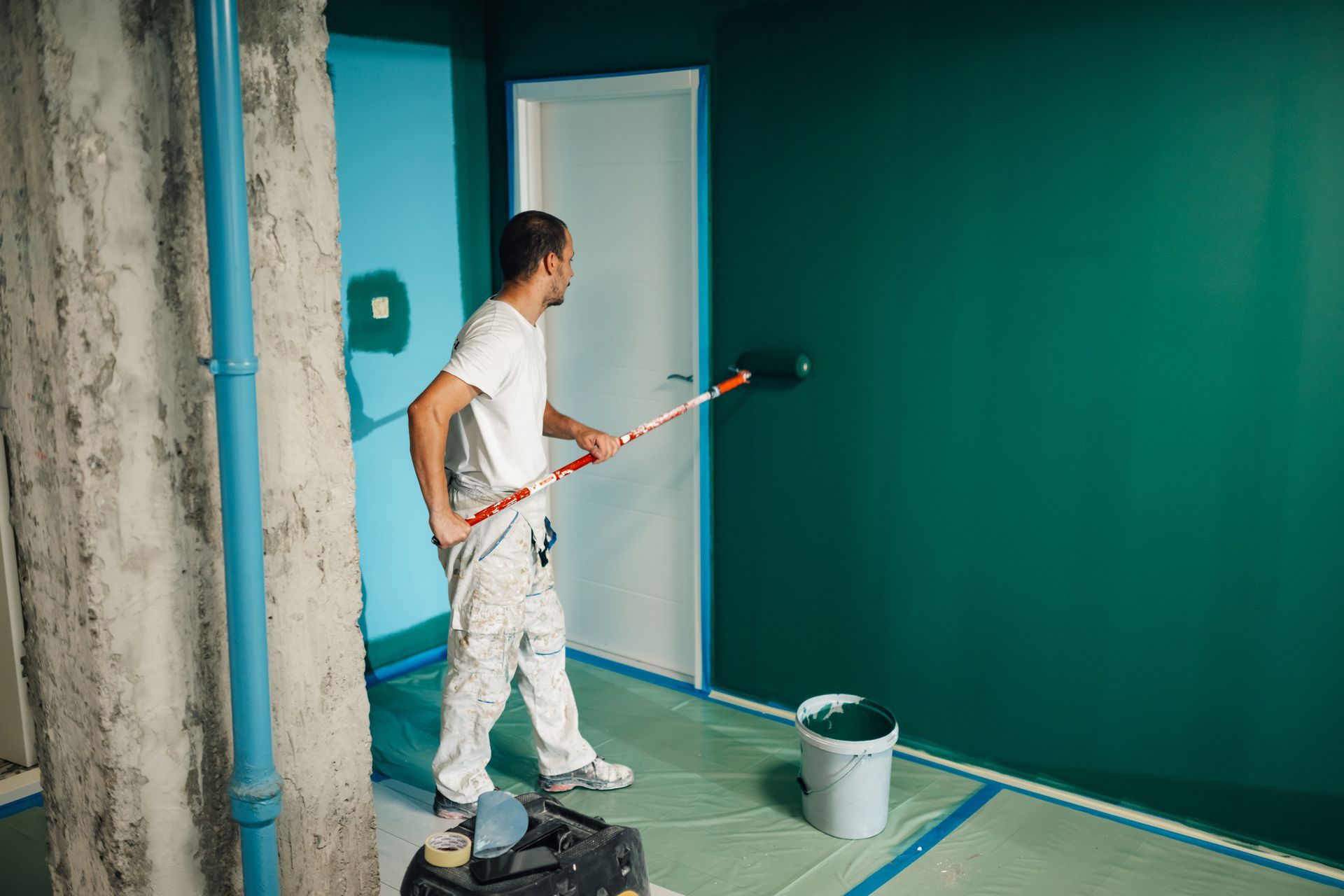 Skilled painter working on a room’s wall using a roller to achieve a smooth, even finish. Skilled painter working on a room’s wall using a roller to achieve a smooth, even finish.