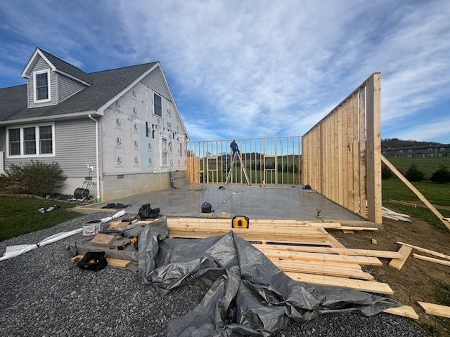 Two people smoothing wet concrete on a newly built patio next to a house.