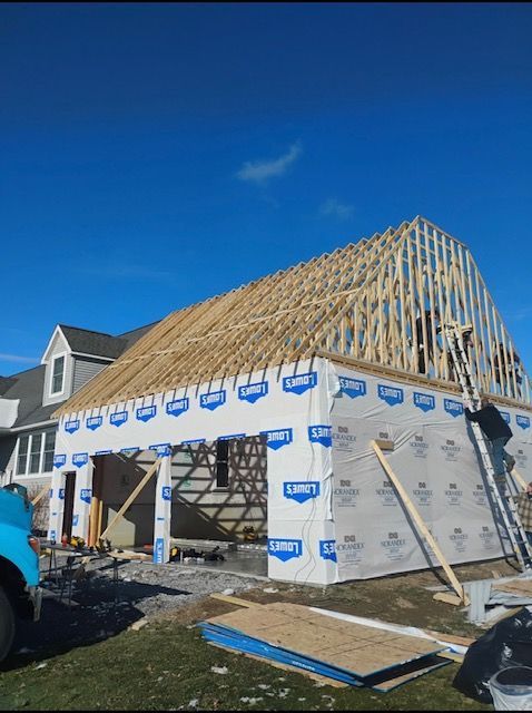 Garage under construction with blue sky; framing and Lowes sheathing visible.