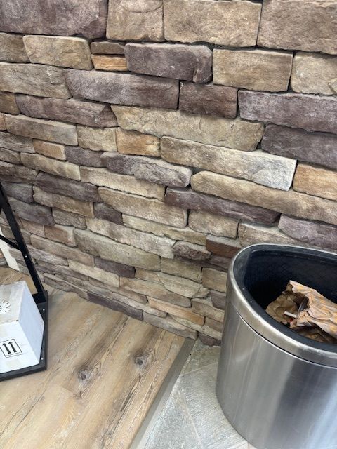 Stone veneer wall with wooden accents, and a metal container. Stone veneer wall with wooden accents, and a metal container.