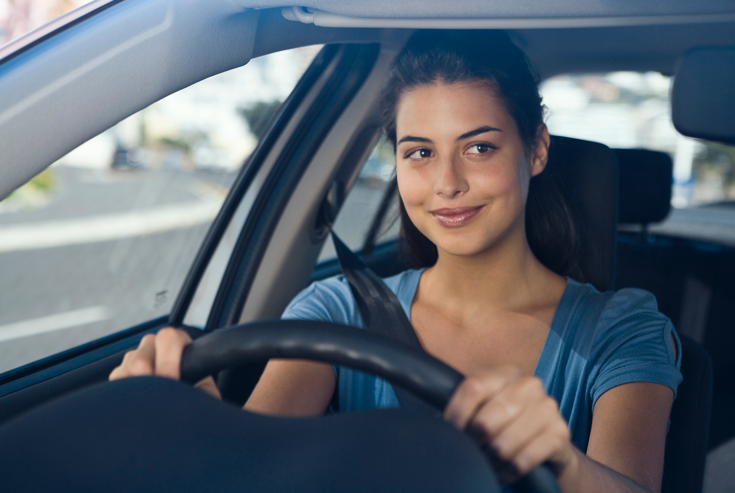 A woman is sitting in the driver 's seat of a car.