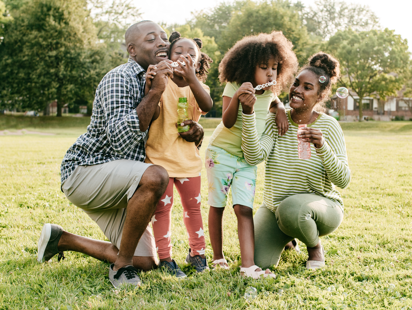 A family is blowing soap bubbles in a park.