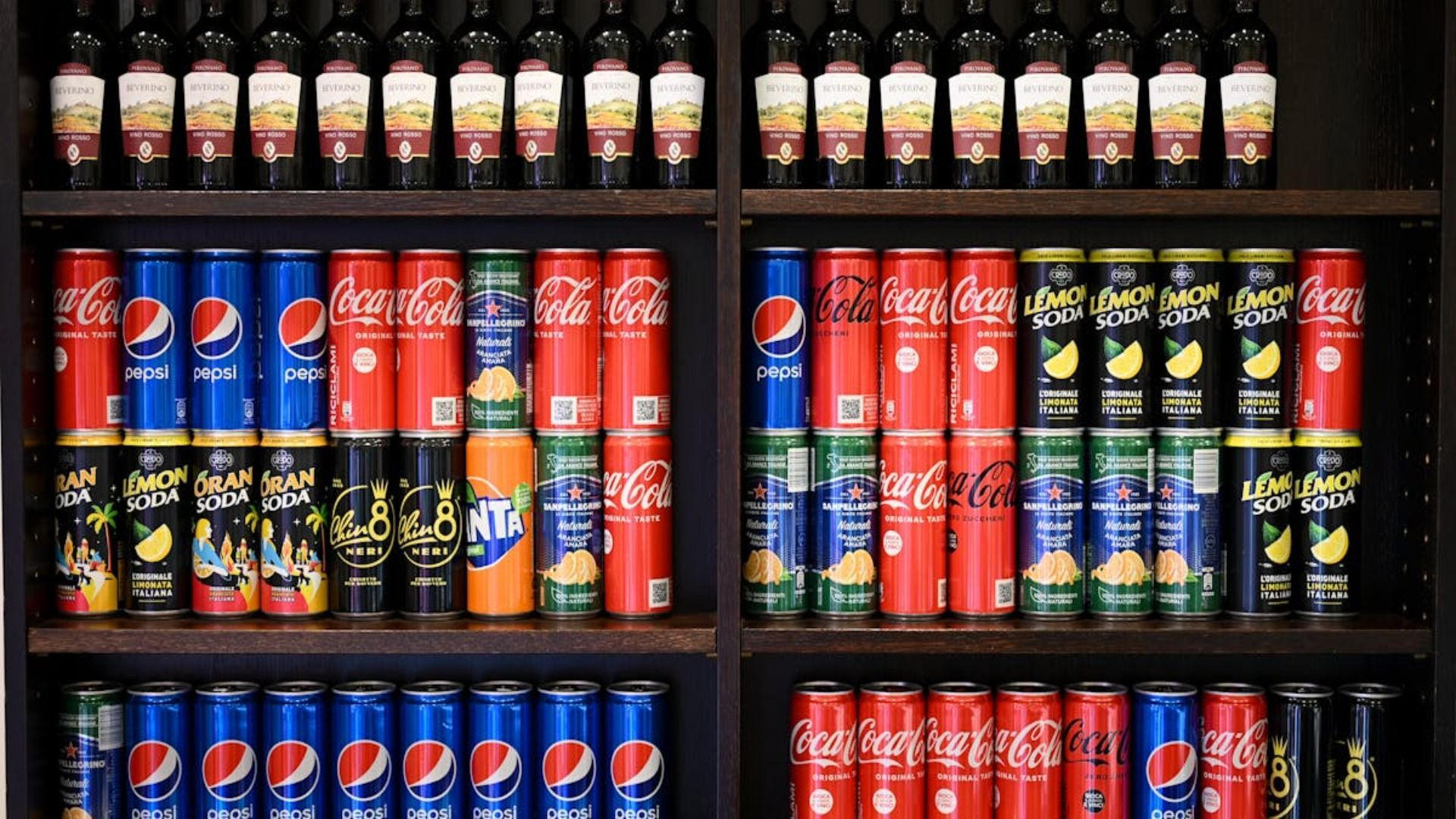 Un estante lleno de latas de refrescos, incluidas Pepsi, Coca Cola y Pringles.