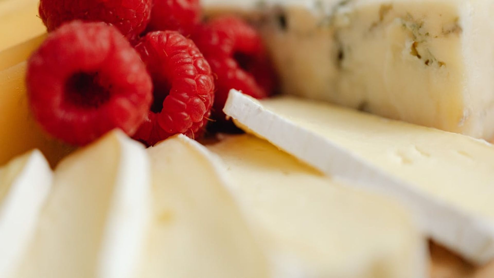 Un primer plano de frambuesas y queso en un plato.