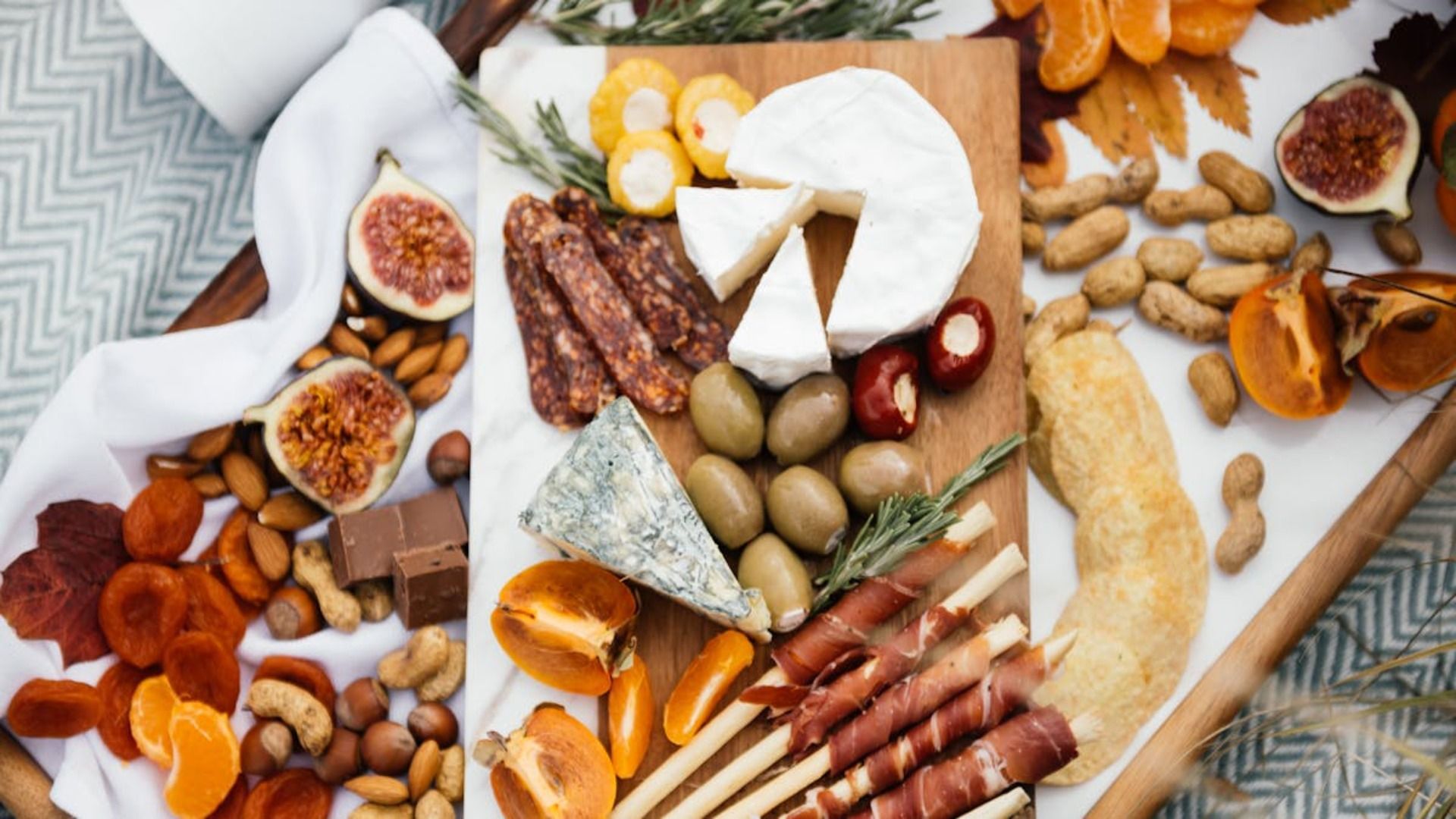 Una tabla de cortar de madera cubierta con queso, nueces y frutas.
