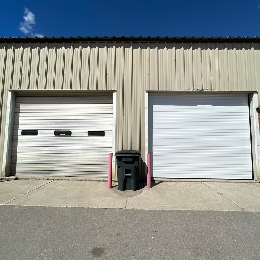 Two garage doors with a trash can in front of them