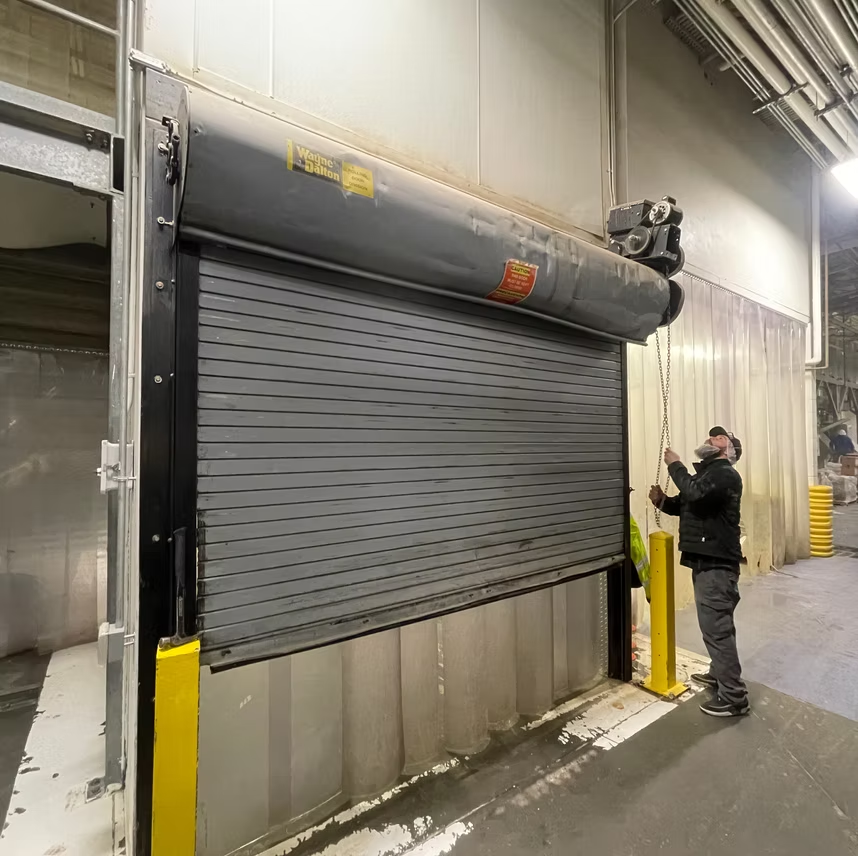 A man is opening a garage door in a building