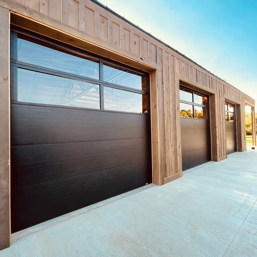 A row of black garage doors with large windows on a building.