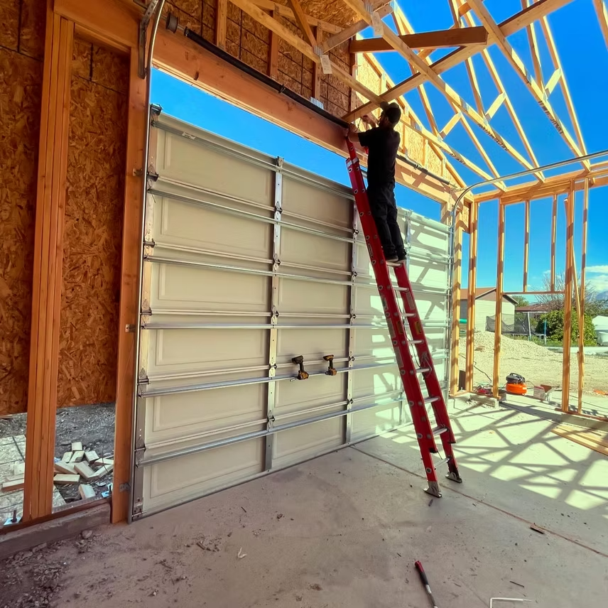 A man on a ladder is working on a garage door