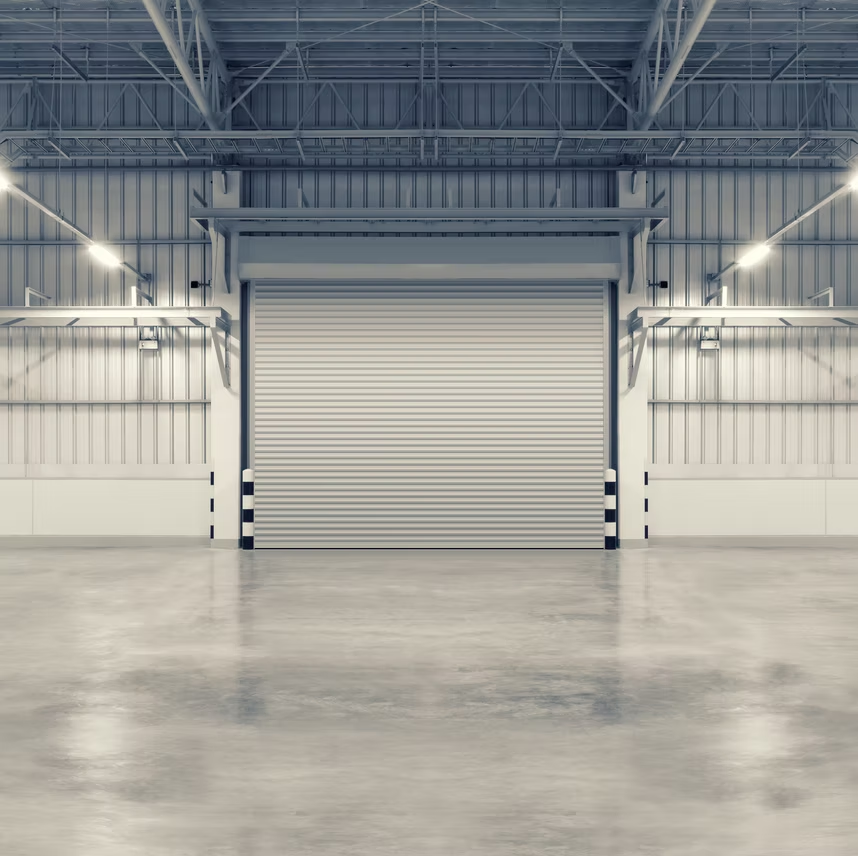 An empty warehouse with a roller shutter door and a concrete floor.