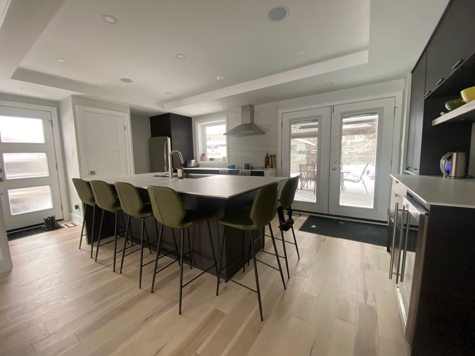 Modern kitchen with a large island, bar stools, and outdoor access.