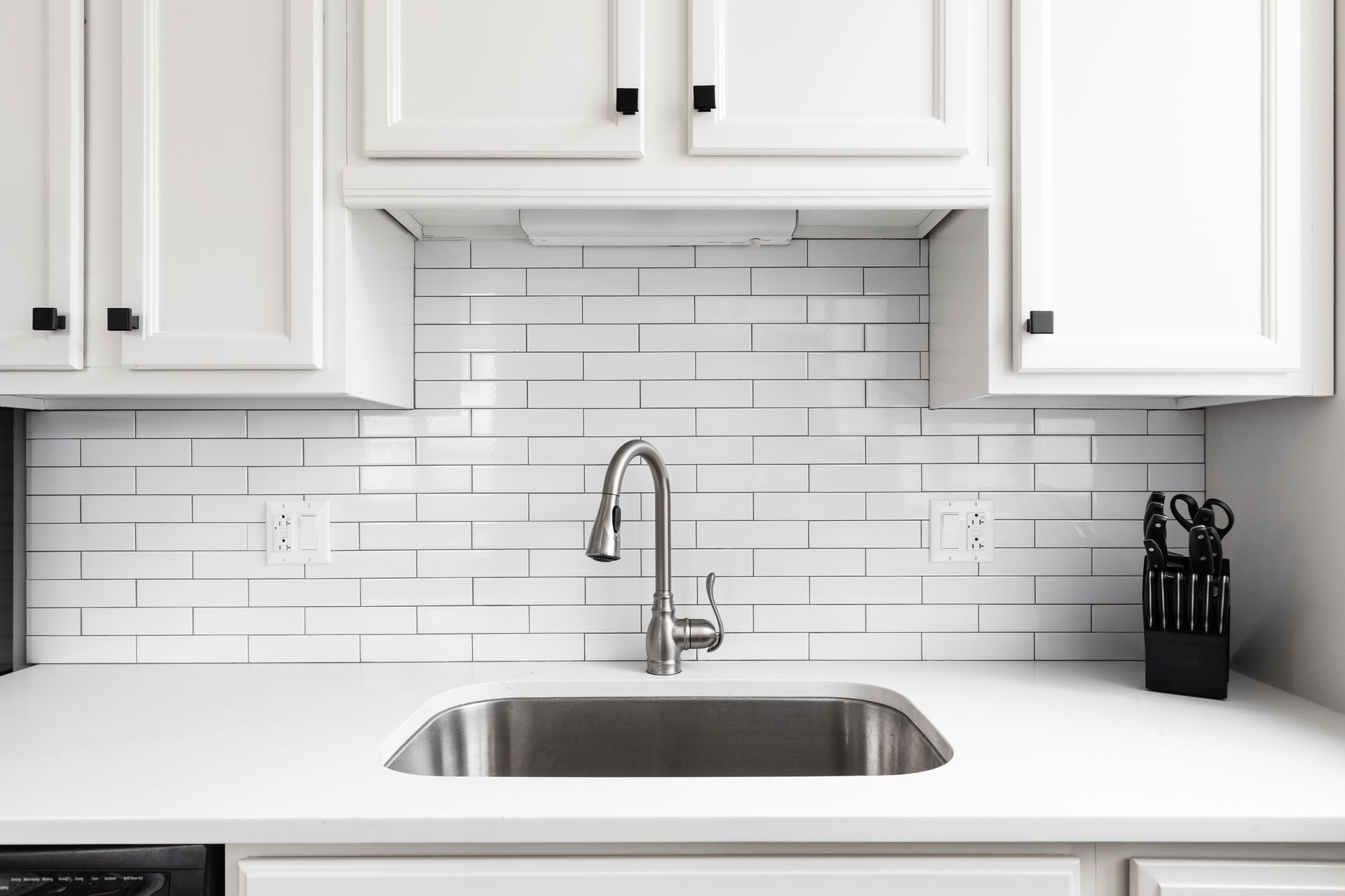 A kitchen with white cabinets and a stainless steel sink.